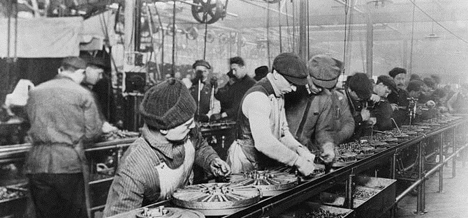 Workers on the first moving assembly line put together magnetos and flywheels for 1913 Ford autos, Highland Park, Michigan / Wikimedia / gemeinfrei