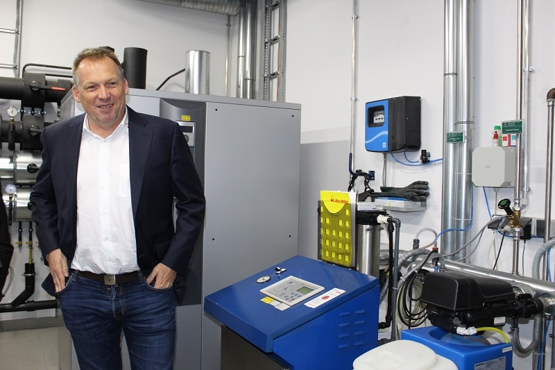 Firmenchef Andreas Müller vor der Steuereinrichtung der Anlage und dem Stromspeicher (hinten).